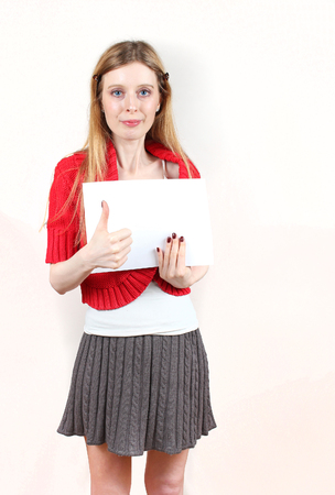 Young woman holding empty white paper with thumb up gesture on the handの写真素材