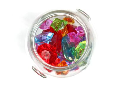 Colorful sparkling diamonds in glass jar on white backgroundの写真素材