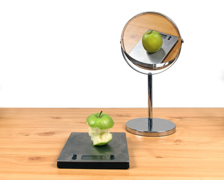 Concept about body image distortion with eaten apple and fat apple in the mirrorの写真素材