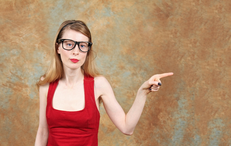 Young woman with eye glasses showing with her index finger where you can use for copy spaceの写真素材