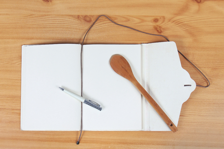 Open notebook with pen for writing recipes and wooden spoonの写真素材
