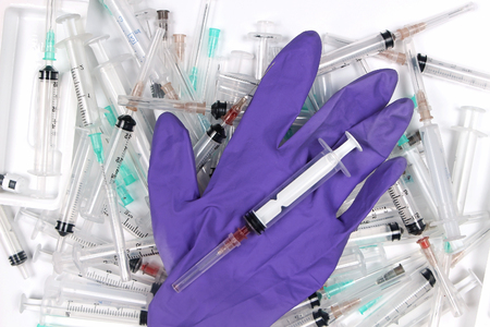 Large used medical syringes pile with surgical gloveの写真素材