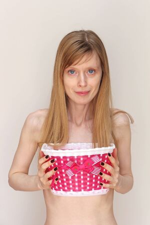 Young blonde woman holding pink basket with bowの写真素材