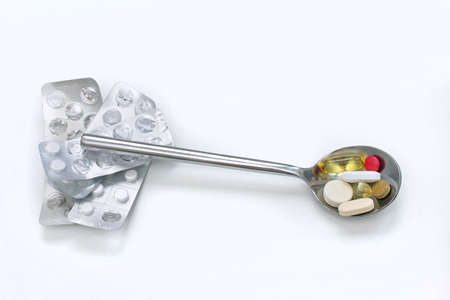 Pile of pills inside spoon on white backgroundの写真素材