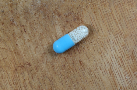 Blue pill capsule on wooden backgroundの写真素材