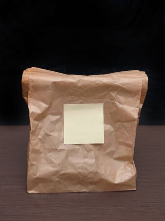Closed paper brown bag with blank noteの写真素材