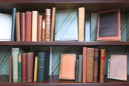 Old book shelf with stacks of vintage booksの写真素材