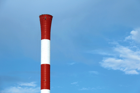 Red and white industrial chimney on blue sky backgroundの写真素材