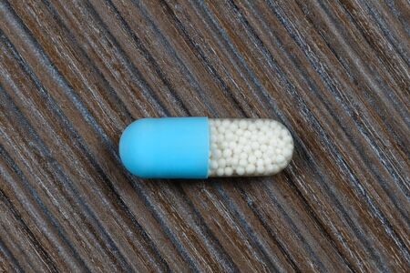 Macro shot of blue capsule on wooden backgroundの写真素材