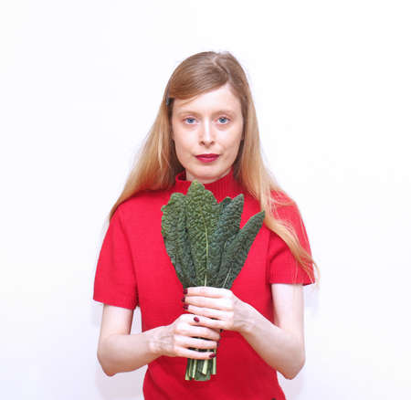 Young blonde woman holding green kale leavesの写真素材