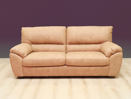 Beige leather sofa inside interior with purple wall and wooden floorの写真素材