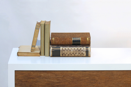 Old vintage hard cover books on white wooden shelfの写真素材