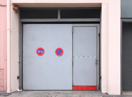 Closed exterior garage door with no parking sign and warningの写真素材