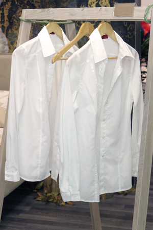 Ironed male clothes white shirts on wooden hangersの写真素材