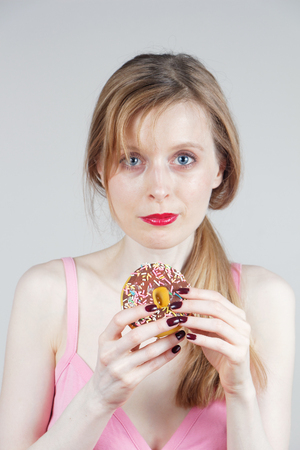 Young beautiful girl holding sweet donut in her handの写真素材