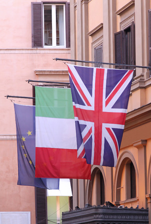 Three international flags hanging from poles on building facadeの写真素材