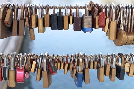 Old rusty padlocks left at the bridge fence as a symbol of eternal loveの写真素材
