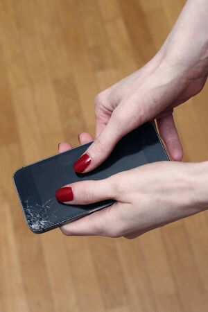 Female hands holding broken smartphone with cracked displayの写真素材