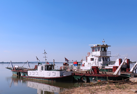 River ferry boat for transport of people and motor vehicles to cross the water moored at shoreの写真素材