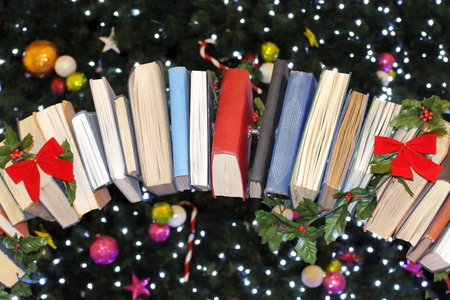 Row of books as Christmas tree ornament with other glowing ornaments blurry background besideの写真素材