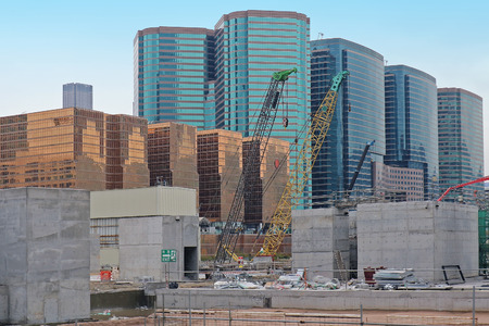 Large modern building construction site with big cranes and finished skyscrapers with glass facades in the backの写真素材