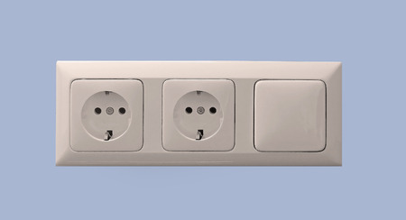 Two European style sockets and light switch on blue interior wall