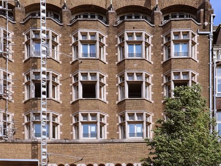 Retro brick wall building facade under renovation with open windowsの写真素材