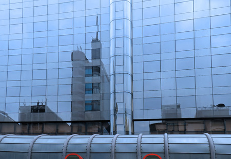 Modern building with glass facade and surrounding buildings reflectionの写真素材
