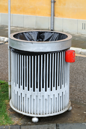 Trash bin in public park with small ashtray attached on the side for smokers to safely dispose of cigarettesの写真素材
