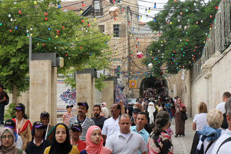 JERUSALEM, ISRAEL - MAY 25, 2018: People walking through old city street in Jerusalem during Muslim Holy month of ramadan pilgrimage on their way to participate in pray with festive lights above them.のeditorial素材
