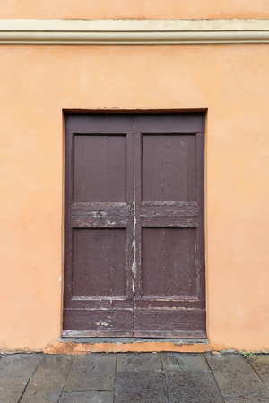 Old dirty closed wooden door entrance with beige facadeの写真素材