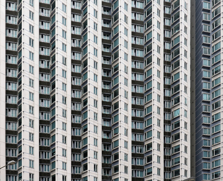Small windows and balconies on tall residential building exterior in Hong Kongの写真素材