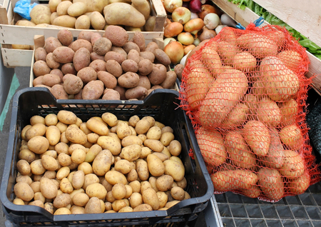 Several different kinds of potato in crates and sack on market stallの写真素材
