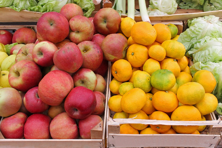 Fresh organic red apples and oranges on market stallの写真素材