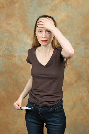 Young woman showing empty pocket with worried face expression and arm on the faceの写真素材