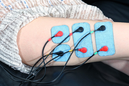 Slimming treatment with electrodes attached to leg thigh muscleの写真素材