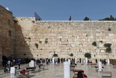 JERUSALEM, ISRAEL - MAY 25, 2018: Group of Jewish people praying in front of ancient limestone wall in the Old City of Jerusalem known as Western Wall as holy due to its connection to the Temple Mount.のeditorial素材