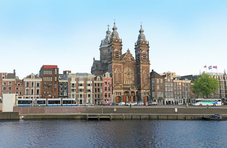 AMSTERDAM, NETHERLANDS - MAY 16, 2018: Amsterdam Central exterior building is the largest railway station of Amsterdam, Netherlands with busy public traffic outside in front of the entrance and people walking towards the trains shot from Amstel river.のeditorial素材