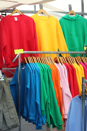Colorful sweatshirts on hangers sold on street marketの写真素材