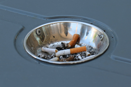 Cigarette butts inside ashtray on top of trash bin in parkの写真素材