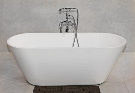 Modern empty bathtub on marble floor with retro silver tapの写真素材