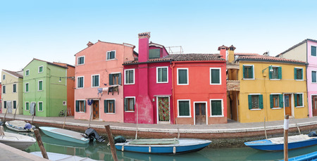 Retro residential houses with colorful facades on Burano island with small boats in canalの写真素材