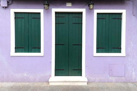 Retro house entrance with colorful facade and closed wooden green door and windowsの写真素材