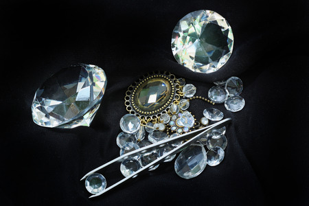 Sparkling diamonds pile on black background with tweezers holding one for authenticationの写真素材
