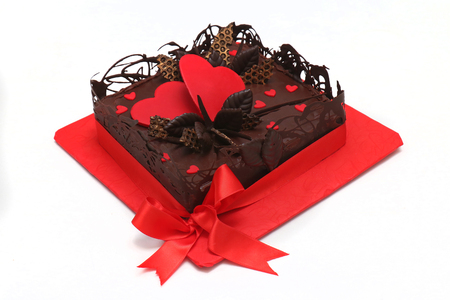 Chocolate cake with red heart decoration isolated on whiteの写真素材