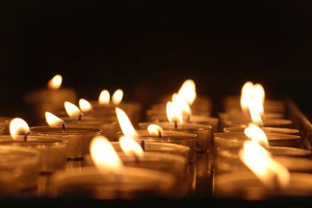 Many candles burning in the religious dark interiorの写真素材