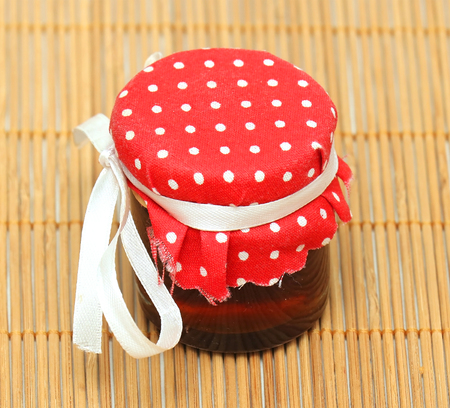 Small jam jar with retro polka dot cover on rattan backgroundの写真素材