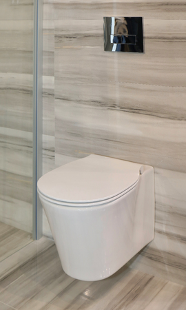 Modern toilet in contemporary bathroom interior with beige tiles