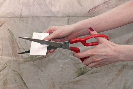 Female hands cutting silver credit chip card with scissorsの写真素材