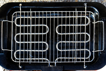 Empty silver metal barbecue grill on black plateの写真素材